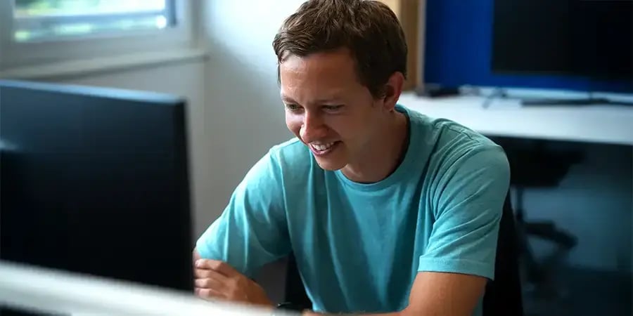Arivo employee sitting in front of two computer screens displaying technical drawings, surrounded by notes.