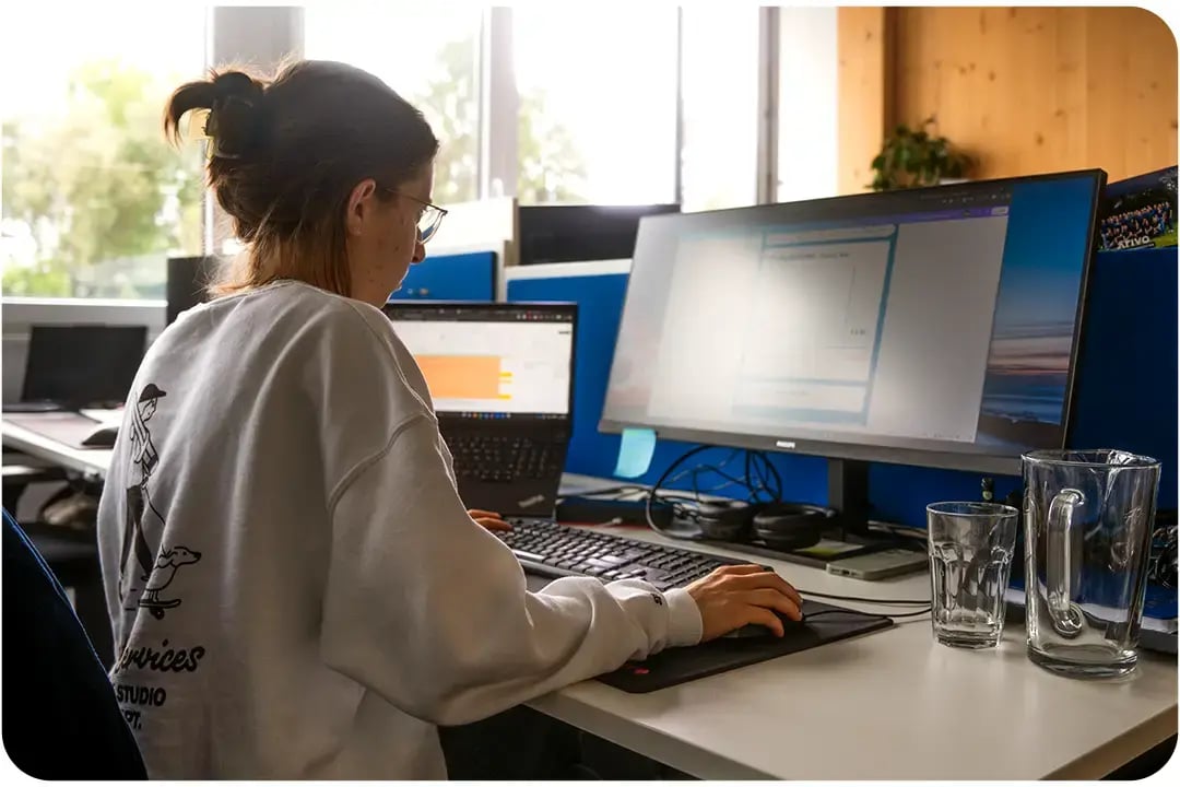 Arivo Marketing-Mitarbeiterin sitzt mit Rücken zur Kamera vor einem Computer-Bildschirm.