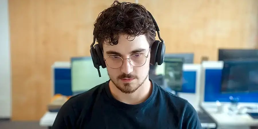 Arivo Support-Mitarbeiter mit Headset-Kopfhörern sitzt vor einem Bildschirm in einem Büro.