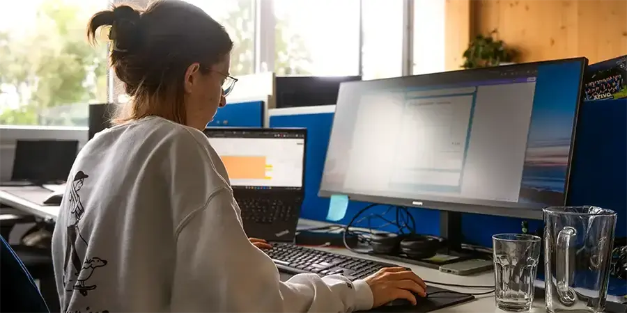 Arivo Marketing-Mitarbeiterin sitzt mit Rücken zur Kamera vor einem Computer-Bildschirm.