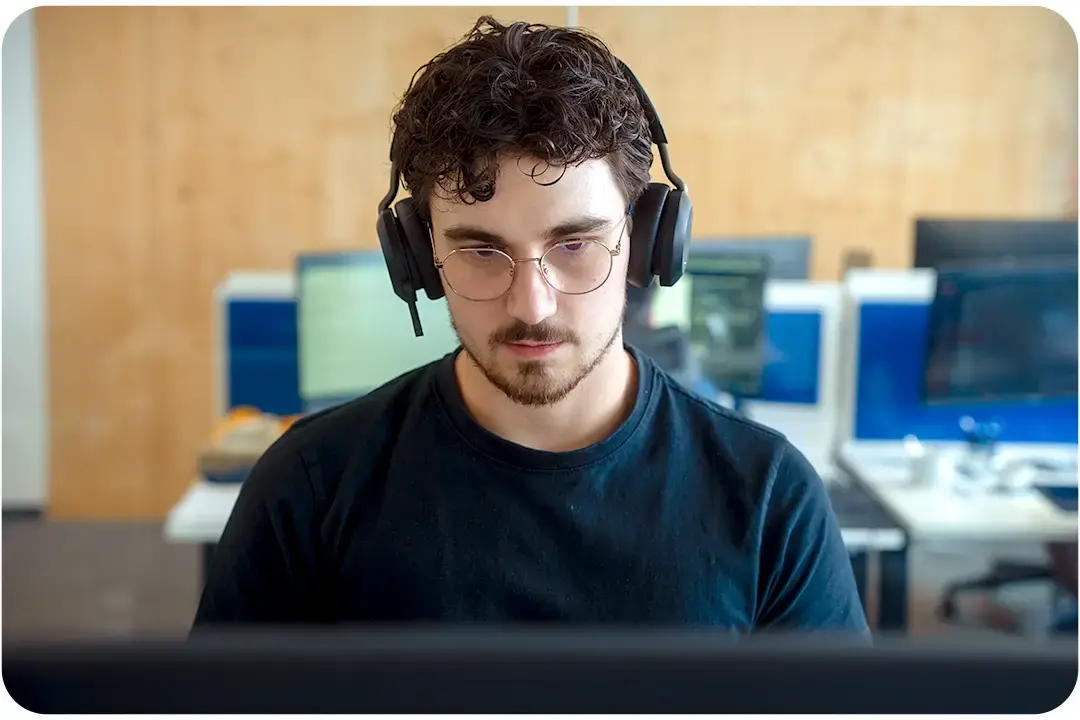 Arivo Support employee wearing headset headphones sitting in front of a screen in an office.